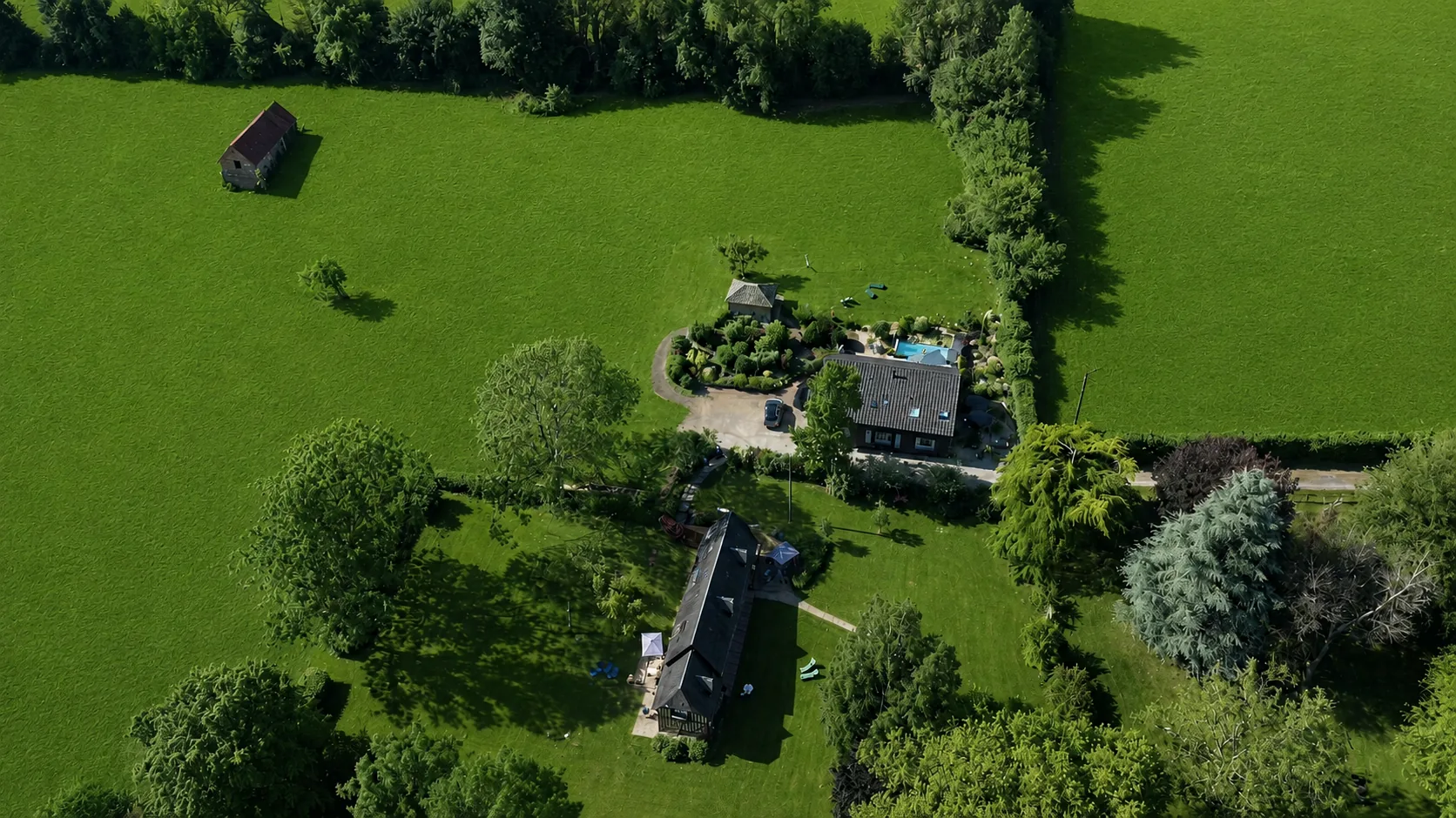 Le Hameau des Prés-Verts vu du ciel : ses maisons, la piscine et le jardin, entre les haies et les prés