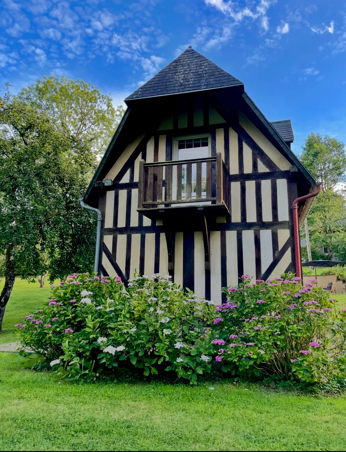 La façade à colombages de Reinette Grise, son balcon de bois et les hortensias