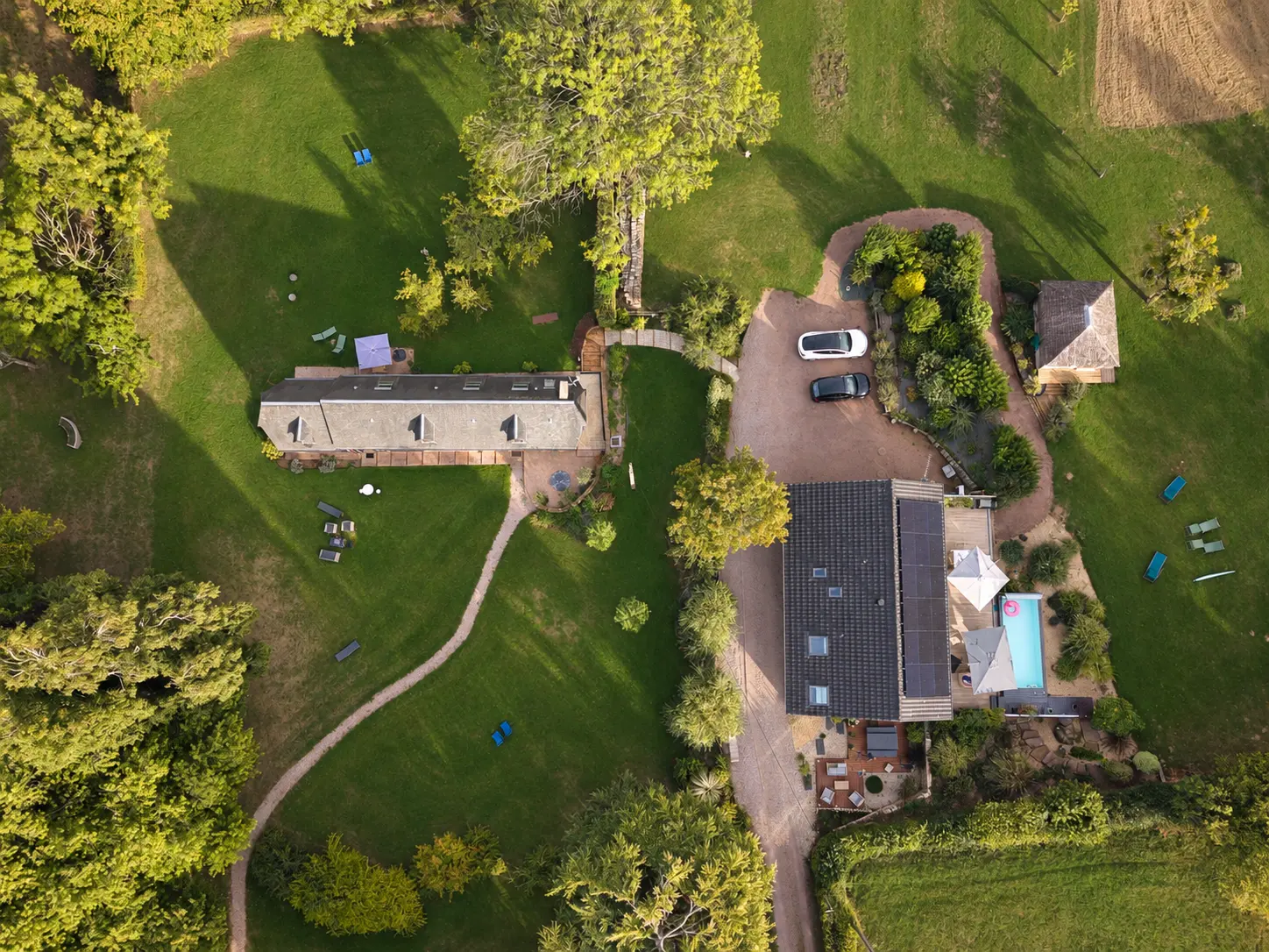Vue aérienne du Hameau : Reinette Grise à gauche, le Chalet Normand et sa piscine en bas à droite, le kiosque du jacuzzi en haut à droite et le parking privatif entre les maisons